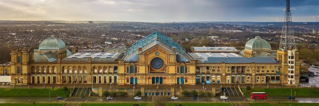 London, England - Aerial panromaic view of Alexandra Palace in Alexandra Park with iconic red double-decker bus and dramatic clouds behind